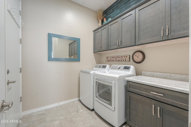 laundry area featuring washer and clothes dryer, light tile patterned floors, and cabinets