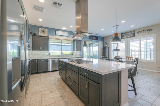 kitchen featuring a center island, island range hood, hanging light fixtures, decorative backsplash, and appliances with stainless steel finishes