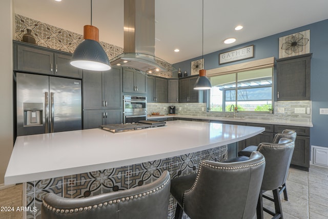 kitchen with pendant lighting, island exhaust hood, backsplash, appliances with stainless steel finishes, and a spacious island