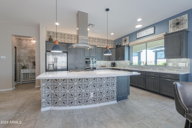 kitchen with hanging light fixtures, sink, island exhaust hood, stainless steel appliances, and a center island