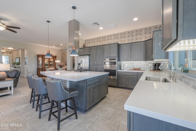 kitchen with hanging light fixtures, a center island, ceiling fan, and sink