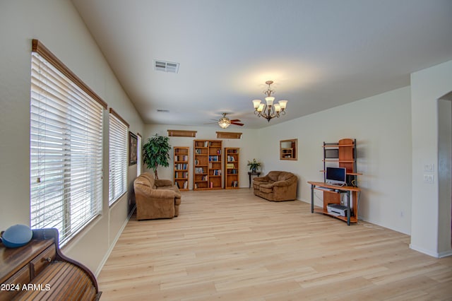 living area with ceiling fan with notable chandelier and light hardwood / wood-style flooring