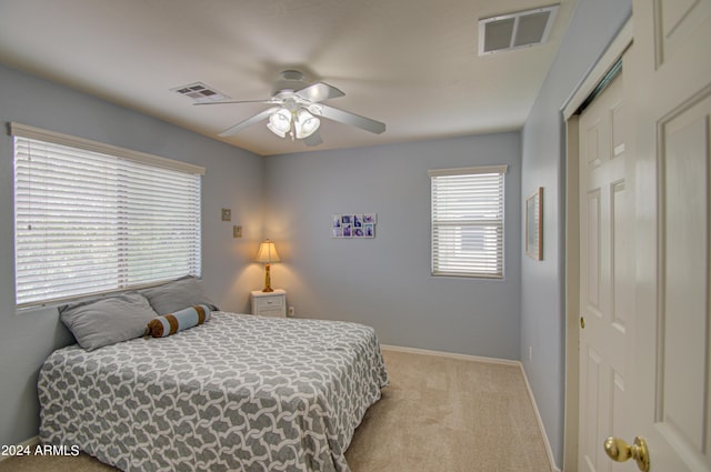 bedroom featuring light colored carpet, a closet, and ceiling fan