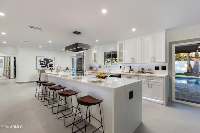 kitchen with white cabinetry, a kitchen island with sink, a breakfast bar area, and light stone countertops