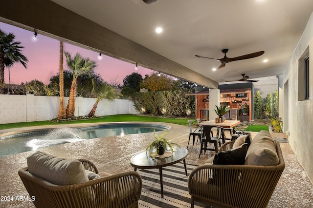 pool at dusk with a patio area, ceiling fan, and an outdoor hangout area