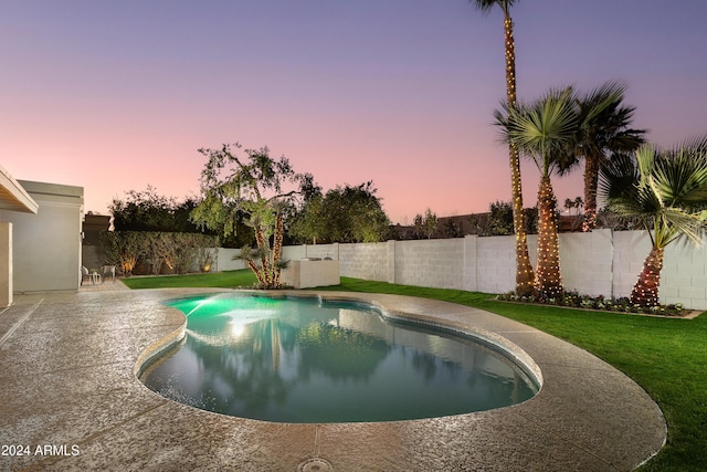 pool at dusk with a lawn and a patio