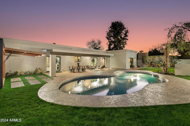 pool at dusk featuring a yard and a patio