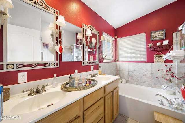 full bathroom featuring lofted ceiling, a garden tub, double vanity, and a sink