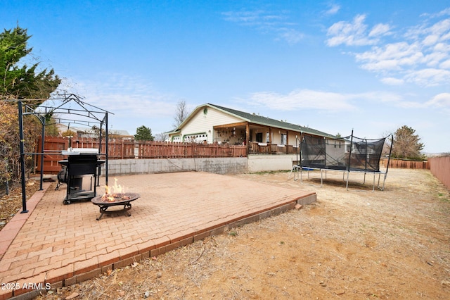 view of yard with a trampoline, an outdoor fire pit, a patio area, and a fenced backyard
