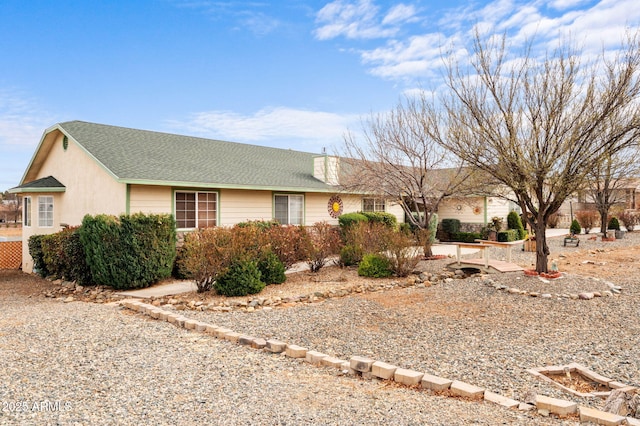 ranch-style home with a shingled roof and a chimney