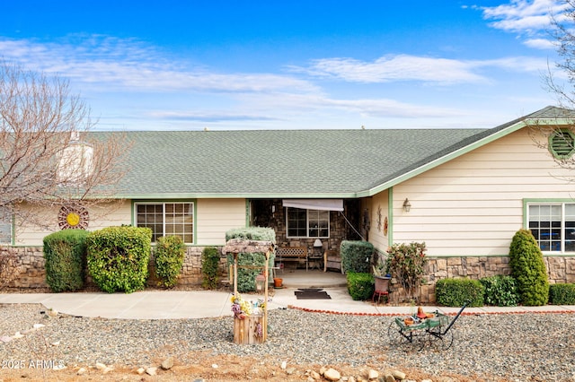single story home with a shingled roof and stone siding