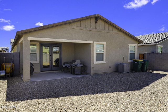 rear view of house with french doors, a tile roof, stucco siding, a patio area, and fence