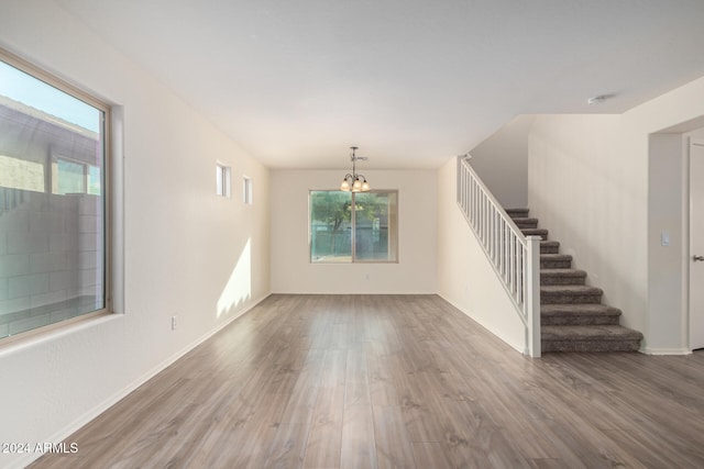 unfurnished living room with a notable chandelier and hardwood / wood-style flooring