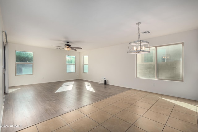 spare room featuring ceiling fan with notable chandelier and light hardwood / wood-style floors