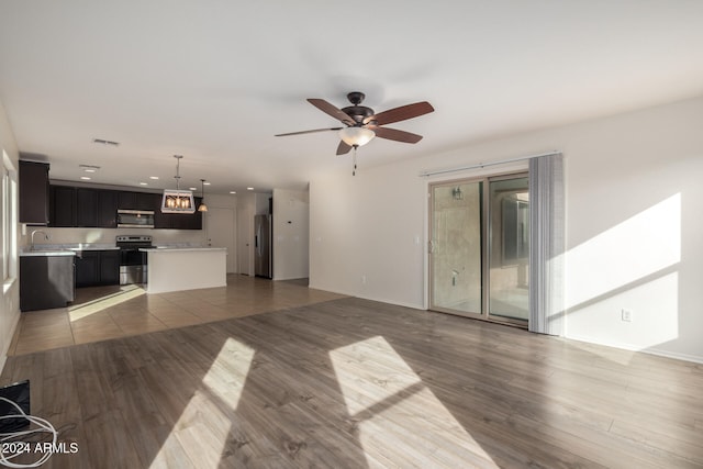 unfurnished living room featuring hardwood / wood-style flooring, ceiling fan, and sink