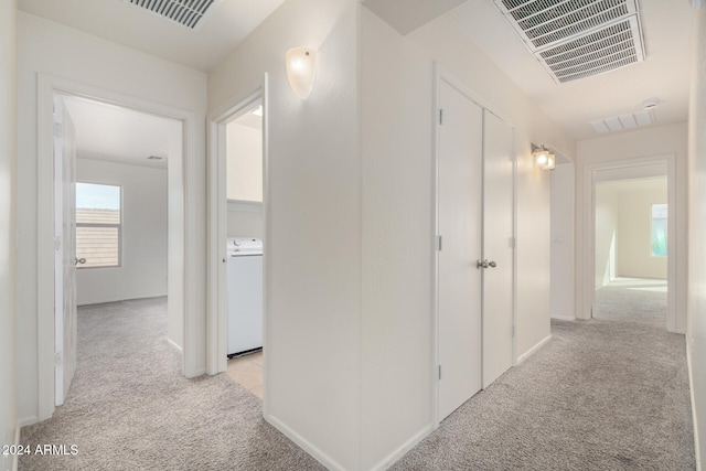 hallway featuring light colored carpet and washer / clothes dryer