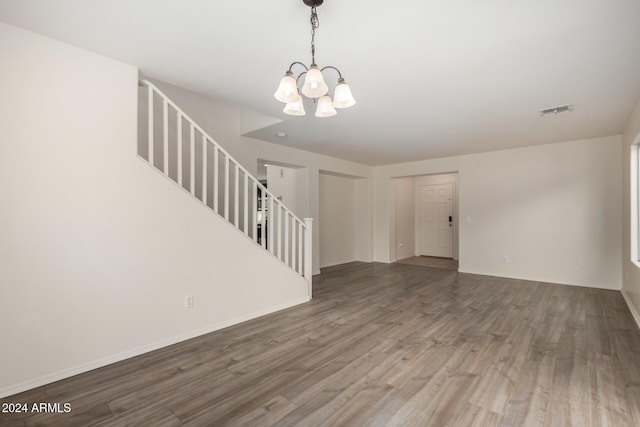 unfurnished living room featuring an inviting chandelier and hardwood / wood-style flooring