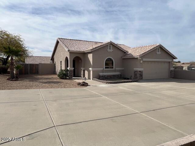 mediterranean / spanish-style house with driveway, fence, a tile roof, and stucco siding