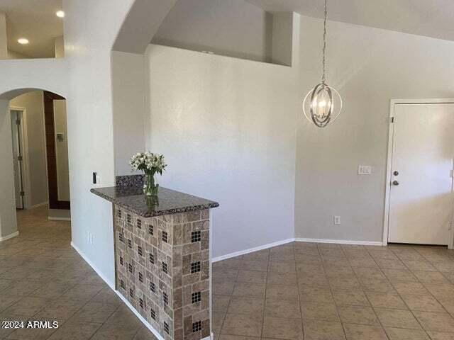 interior space with high vaulted ceiling, baseboards, arched walkways, and a notable chandelier