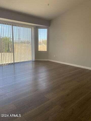 empty room featuring dark wood-type flooring and baseboards