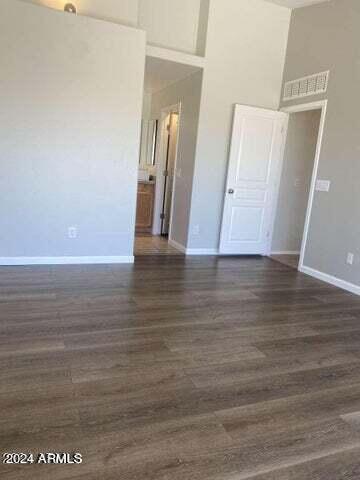 spare room featuring a high ceiling, dark wood-style flooring, and baseboards