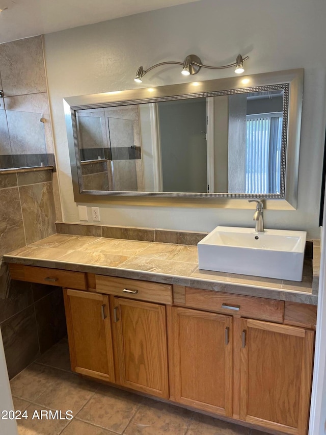 bathroom with tile patterned floors, a tile shower, and vanity