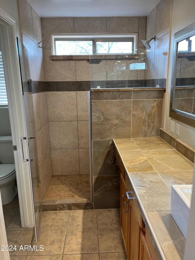 full bath with tiled shower, vanity, and toilet