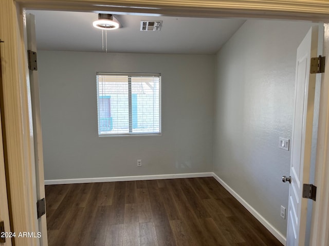 spare room featuring visible vents, dark wood finished floors, and baseboards