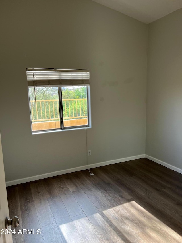 spare room with baseboards and wood finished floors