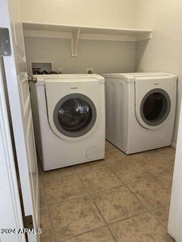 clothes washing area with laundry area, light tile patterned flooring, and washing machine and clothes dryer