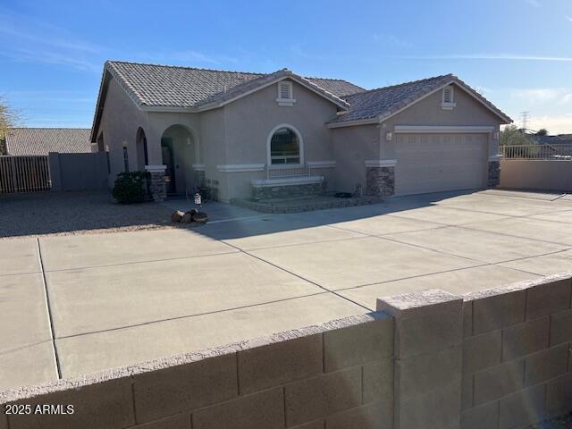 view of front of home featuring a garage, fence, concrete driveway, and stucco siding