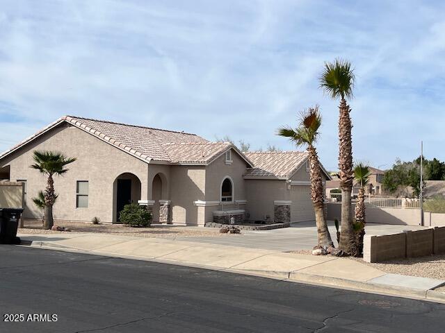 mediterranean / spanish-style home featuring driveway, a tiled roof, fence, and stucco siding