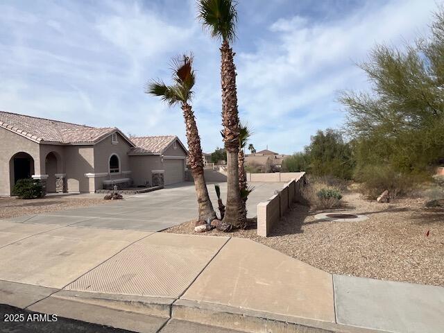 view of property exterior with an attached garage, stucco siding, concrete driveway, and a tiled roof