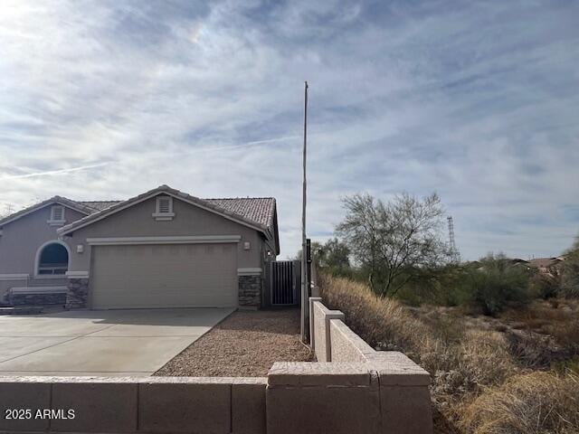 view of front of house featuring driveway, stone siding, an attached garage, and stucco siding