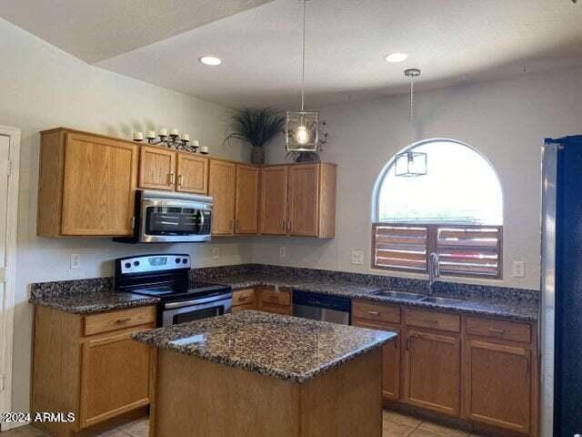 kitchen with dark stone counters, appliances with stainless steel finishes, brown cabinetry, and a sink