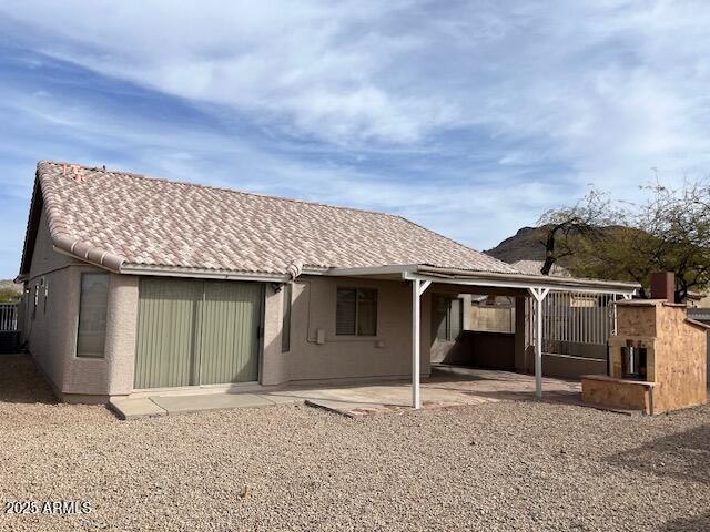 back of house with a tiled roof and a patio