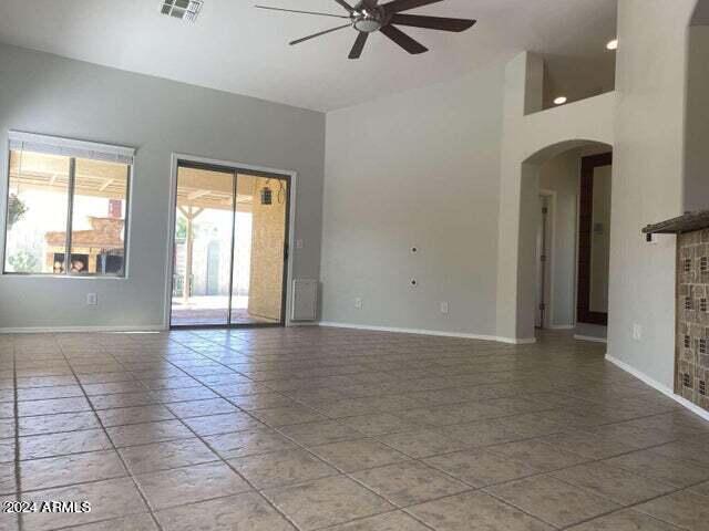 spare room with arched walkways, visible vents, a towering ceiling, a ceiling fan, and baseboards