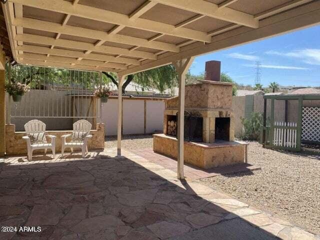 view of patio with fence and an outdoor stone fireplace