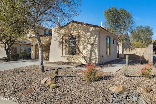 mediterranean / spanish-style home with fence, driveway, an attached garage, stucco siding, and a tiled roof