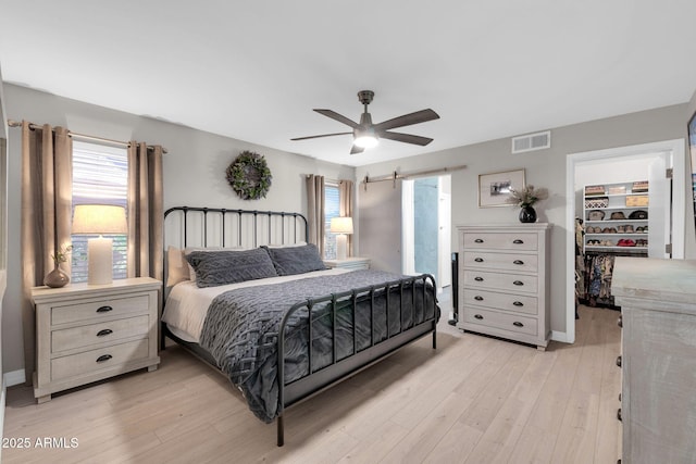 21640 N 48th St, Phoenix, AZ 85054 - bedroom featuring a barn door, visible vents, a spacious closet, multiple windows, and light wood finished floors