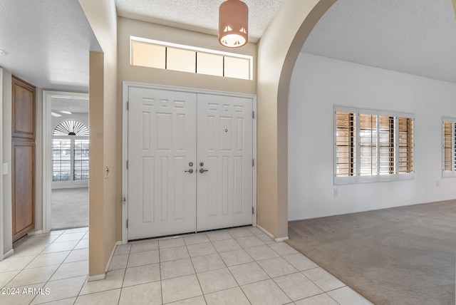 foyer entrance featuring light tile patterned floors and a textured ceiling