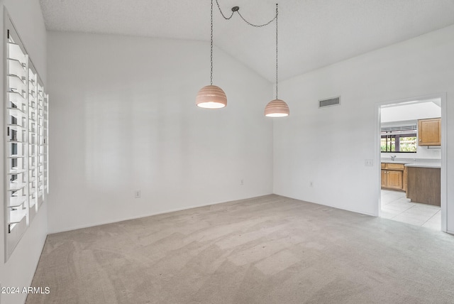 carpeted empty room featuring high vaulted ceiling, sink, and a textured ceiling