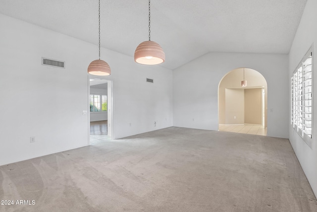 carpeted empty room with high vaulted ceiling