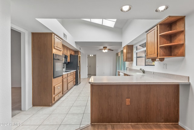 kitchen with wall oven, sink, light tile patterned flooring, kitchen peninsula, and stainless steel fridge with ice dispenser