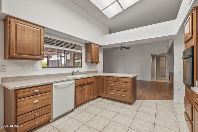 kitchen with ceiling fan, white dishwasher, sink, kitchen peninsula, and black oven