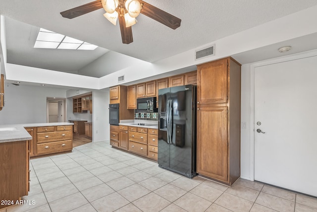 kitchen with light tile patterned flooring, ceiling fan, vaulted ceiling, black appliances, and a textured ceiling