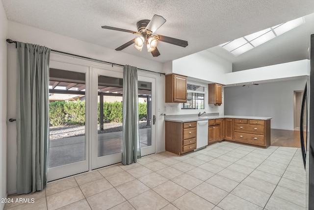 kitchen with white dishwasher, kitchen peninsula, vaulted ceiling, and light tile patterned flooring