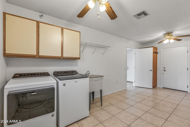 washroom featuring a textured ceiling, ceiling fan, washing machine and clothes dryer, and cabinets