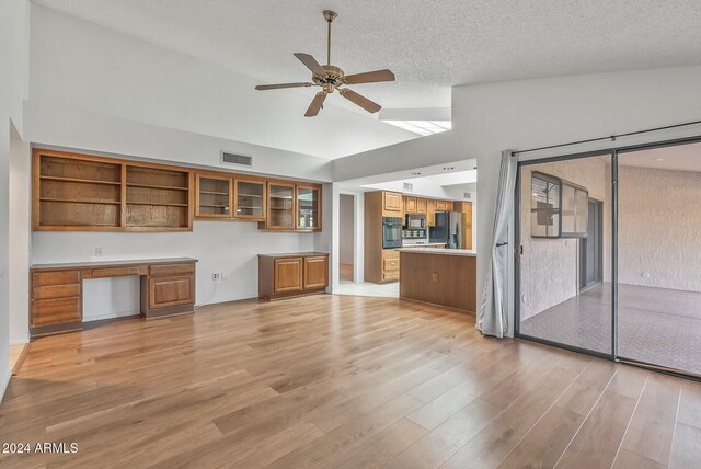 kitchen with light wood-type flooring, ceiling fan, vaulted ceiling, built in desk, and appliances with stainless steel finishes