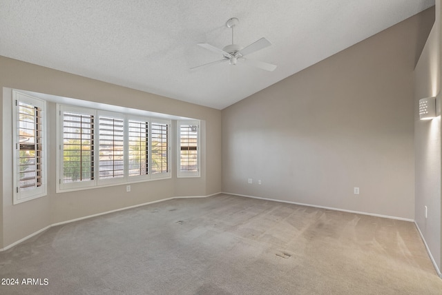 spare room with lofted ceiling, ceiling fan, a textured ceiling, and light carpet